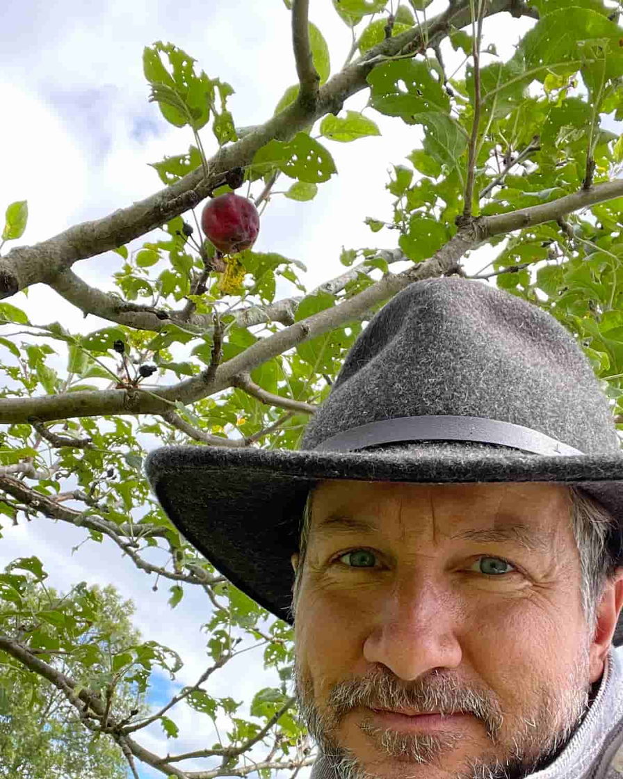 David All — Upper Arlington Tree Co. — in a felt hat beneath an apple branch in the family orchard